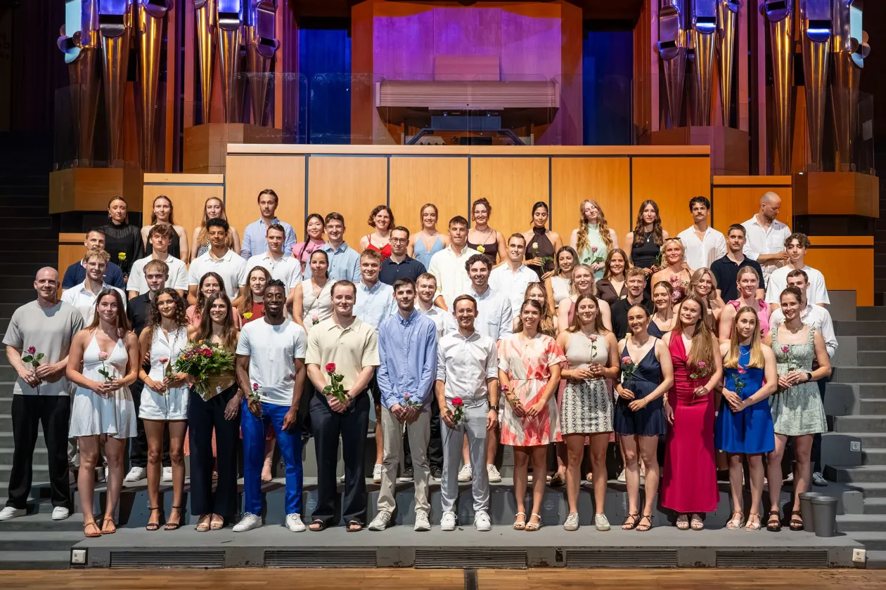 Gruppenfoto der Absolventinnen und Absolventen bei RUB Finish 2026 auf der Bühne des Audimax der RUB